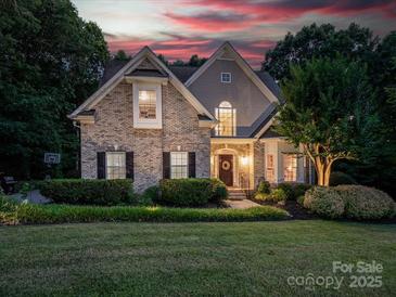 Charming two-story home with brick facade, manicured lawn, and mature landscaping with warm sunset lighting at 821 Lynnwood Farms Dr, Fort Mill, SC 29715