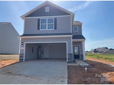 Two-story home featuring a grey exterior, open garage and professionally landscaped front yard at 102 Lightning Dr, Shelby, NC 28152