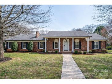 Charming brick home featuring a well-manicured lawn, inviting entryway, and classic architectural details at 104 N Hawthorne St, Mount Holly, NC 28120