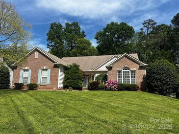 Charming brick home with light blue shutters, a well-manicured lawn, and beautiful landscaping at 10829 Carmody Ct, Charlotte, NC 28277
