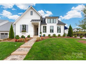 Charming white home with manicured lawn, flower beds, and a inviting brick pathway at 13217 Oak Farm Ln, Huntersville, NC 28078