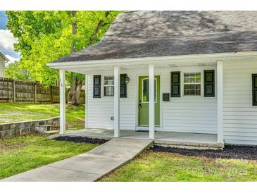Charming home with a well-manicured lawn, covered front porch and a green front door at 210 Knox St, Clover, SC 29710