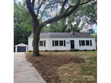 Charming single-story home with black shutters and a detached garage, nestled under mature trees at 1003 Woodland Dr, Gastonia, NC 28054