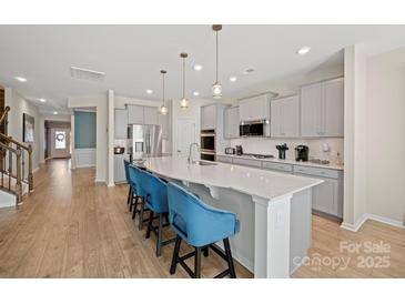 Bright kitchen features a large island with bar seating, stainless steel appliances, and stylish pendant lighting at 168 Kennerly Center Dr, Mooresville, NC 28115