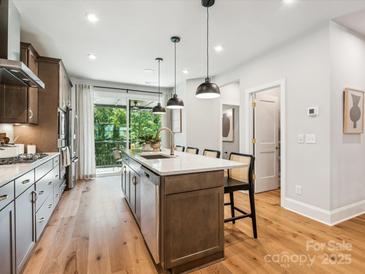 Modern kitchen with a large island, stainless steel appliances, and a door to the outdoor balcony overlooking a wooded area at 408 Old Town Village Rd, Waxhaw, NC 28173