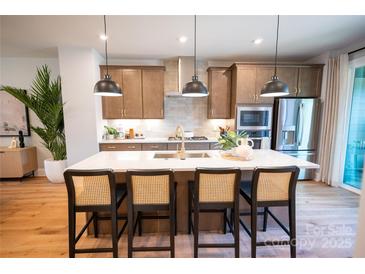 Bright kitchen featuring a quartz island with seating and modern stainless-steel appliances at 408 Old Town Village Rd, Waxhaw, NC 28173