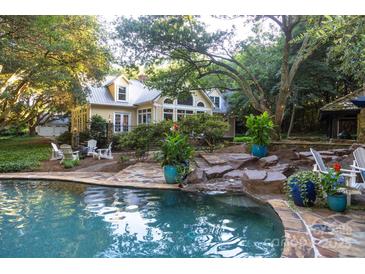 Beautiful pool area featuring stone accents, lush landscaping and mature trees, perfect for relaxing and entertaining at 7794 Live Oaks Dr, Denver, NC 28037