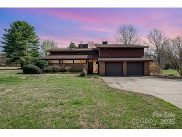 A brick home with a large front yard and an attached three car garage under a pink and purple sky at 190 Country Dr, Statesville, NC 28625