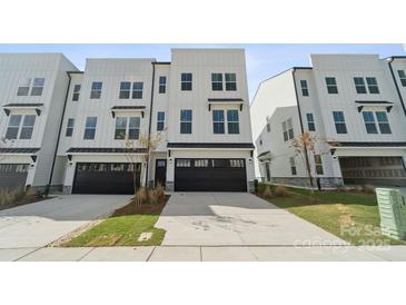 New construction townhome featuring a two-car garage, neutral landscaping, and modern curb appeal at 9239 Delancey Nw Ln, Concord, NC 28027