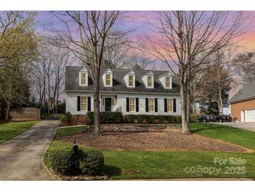 Charming traditional home featuring black shutters, dormer windows, well-maintained lawn, and tasteful landscaping at 10332 Hollybrook Dr, Charlotte, NC 28277