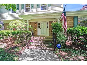 Inviting brick home entrance with American flag, landscaped shrubs and front steps at 1327 Cedarwood Ln, Charlotte, NC 28212