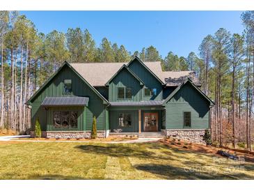 Stunning two-story home featuring green siding, a stone foundation, and beautifully landscaped front yard at 157 Silver Falls Dr, Troutman, NC 28166