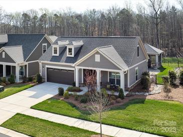 Charming single-story home featuring a two-car garage, dormer windows, and inviting front porch with a landscaped garden at 2011 Trailwood Dr, Matthews, NC 28104