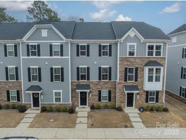 A detailed view of the townhome exteriors featuring stone accents, neutral paint, and black window shutters at 3104 Timber Mill Dr, Matthews, NC 28104
