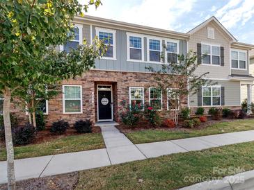 Charming townhome featuring a stone facade, black front door, and landscaped front yard at 426 Kenwood Vw, Indian Trail, NC 28079