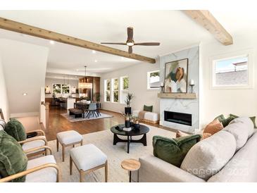 Bright, open living room features hardwood floors, wooden beams, and a modern fireplace with marble surround at 1119 N Myers St, Charlotte, NC 28206