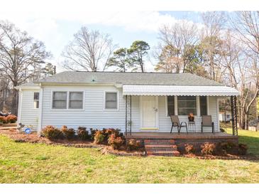 Charming one-story home featuring a cozy covered porch with seating area and well-maintained landscaping at 1404 Lane Rd, Mount Holly, NC 28120