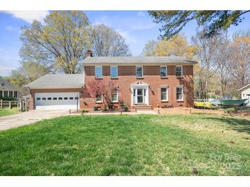 Charming two-story brick home with lush green lawn and mature trees, offering classic curb appeal at 16417 Grapperhall Dr, Huntersville, NC 28078