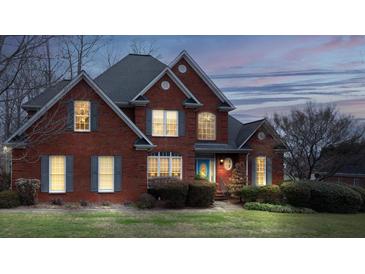 Charming two-story red brick home with manicured lawn and inviting blue front door at dusk at 3516 Araglin Dr, Gastonia, NC 28056