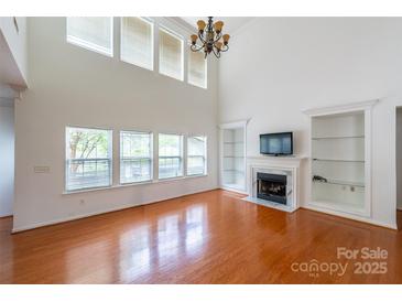 Bright living room features a fireplace, built-in shelving, and large windows offering natural light at 4036 Sawmill Trace Dr, Charlotte, NC 28213