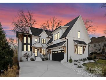 Stunning two-story home featuring white brick, black trim, a dark garage door, and a concrete driveway at 680 Ideal Way, Charlotte, NC 28203