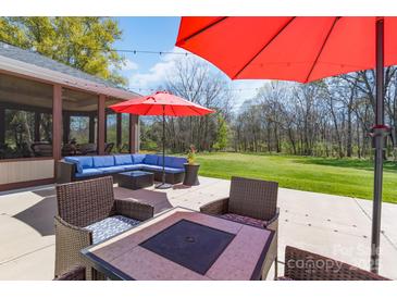 Inviting patio area featuring stylish outdoor furniture and vibrant red umbrellas for comfortable outdoor living at 8201 Tonawanda Dr, Charlotte, NC 28277