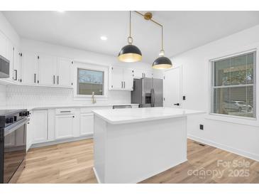 Modern kitchen with stainless steel appliances, island, and white cabinetry at 9930 Sardis Oaks Rd, Charlotte, NC 28270