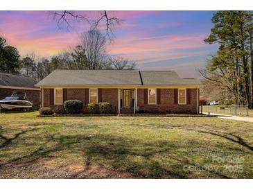 Charming single-story brick home with manicured lawn and mature trees, bathed in the warm glow of the setting sun at 11018 Despa Dr, Mint Hill, NC 28227