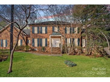 Charming two-story brick home with lush green lawn and mature trees, a welcoming facade with a double door entrance at 1624 Chadmore Nw Ln, Concord, NC 28027