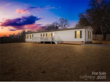 Inviting single-story home with a classic white facade and a charming front porch at dusk at 4055 10Th Avenue Sw Dr, Hickory, NC 28602