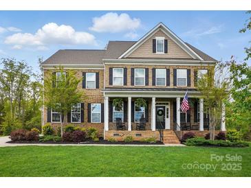 Charming brick home featuring a welcoming front porch with rocking chairs and an American flag at 5140 Oak Grove Pl, Waxhaw, NC 28173