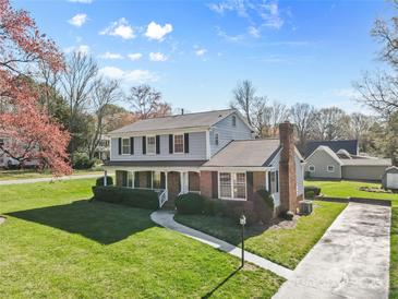 Charming two-story home featuring a brick chimney, covered porch, and a lush, well-manicured lawn at 9218 Robert Burns Ct, Charlotte, NC 28213