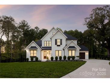 Stunning two-story white brick home featuring a beautifully landscaped front yard and a charming, covered front porch at 2013 Garden View Ln, Weddington, NC 28104