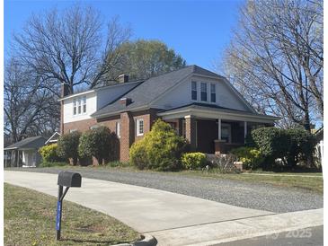Charming brick home with landscaped front yard and long concrete driveway on a sunny day at 312 Gold Hill Ave, Rockwell, NC 28138