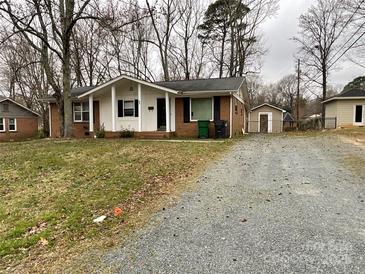 Charming single-story brick home with a well-maintained front yard and a gravel driveway at 837 Corwin Dr, Charlotte, NC 28213