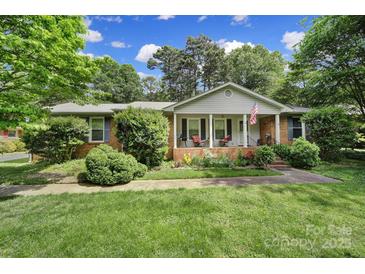 Charming one-story home featuring a brick facade, manicured lawn, and inviting front porch at 8509 Anette Ave, Mint Hill, NC 28227