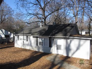 View of the one-story home with a concrete walkway, light gray exterior and dark roof at 1138 Choyce Ave, Charlotte, NC 28217