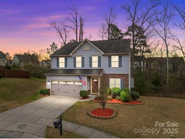 Charming two-story home with blue siding, stone accents, and a well-manicured front yard at dusk at 12302 Volusia Ct, Charlotte, NC 28262