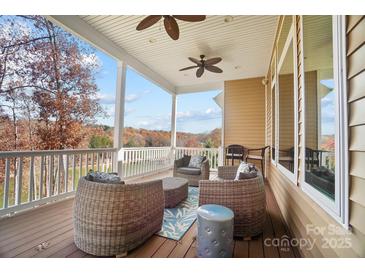 Inviting covered deck featuring wicker furniture and serene lake views perfect for relaxing outdoors at 226 Hermance Ln, Mooresville, NC 28117