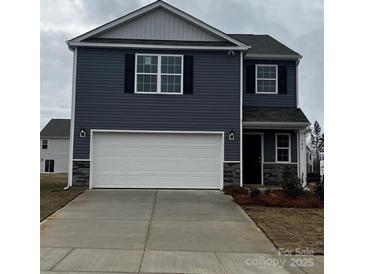 Two-story home featuring a two-car garage, blue siding, and decorative stone accents at 586 N Sparkleberry St, Chester, SC 29706