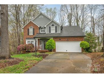 Charming two-story brick home featuring an attached two-car garage and well-manicured landscaping at 9238 Heritage Woods Pl, Charlotte, NC 28269
