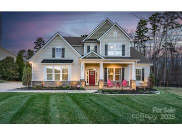 Charming two-story home with a manicured lawn and inviting front porch with bright red chairs at 1005 Palace Ct # 58, Indian Trail, NC 28079