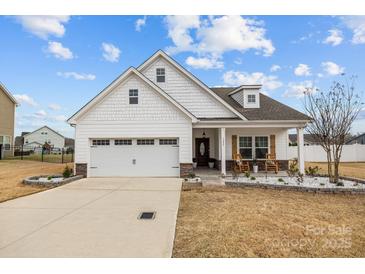 Charming, single story home features a manicured lawn, two-car garage, and covered porch with rocking chairs at 1205 Brooksland Pl, Waxhaw, NC 28173