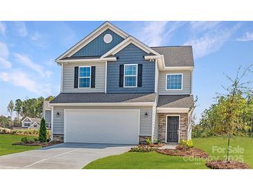 Charming two-story home with a two-car garage, manicured lawn, and colorful flower beds at 15311 Lake Ridge Rd, Charlotte, NC 28278