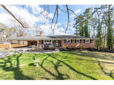 Charming brick home featuring a covered porch and carport, complemented by a lush green lawn and mature trees at 2540 Deal Rd, Mooresville, NC 28115