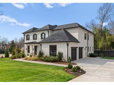 Elegant white brick home features a manicured lawn, dark shutters, and a convenient two-car attached garage at 300 Mammoth Oaks Dr, Charlotte, NC 28270