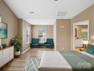 Spacious bedroom featuring hardwood floors, blue accent chairs, and neutral wall paint at 3140 S Legacy Park Blvd, Fort Mill, SC 29707