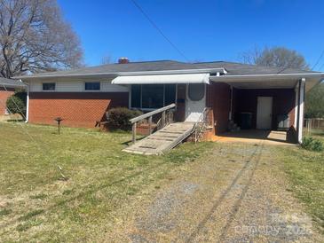 Charming brick house with a ramp, covered entrance, and mature trees under a blue sky at 1403 Oakwood Ave, Kannapolis, NC 28081