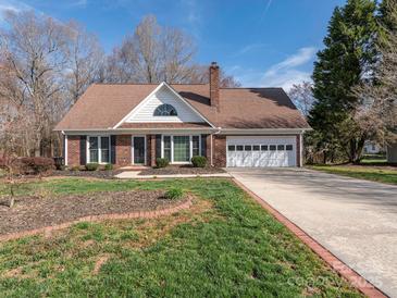 Charming brick home featuring an attached two-car garage, manicured front lawn, and traditional architectural details at 3274 Roberta Farms Sw Ct, Concord, NC 28027