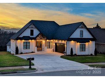 Charming two-story home with a well-manicured lawn, brick facade, and a dark roof during the sunset at 4412 Holly Ne Cir, Conover, NC 28613